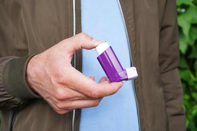 Здоровье и медицинская концепция Мужская рука держит ингалятор от астмы при атаке на открытом воздухе крупным планом