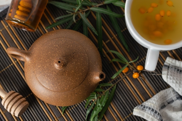 Health natural sea buckthorn tea with honey on a table with teapot
