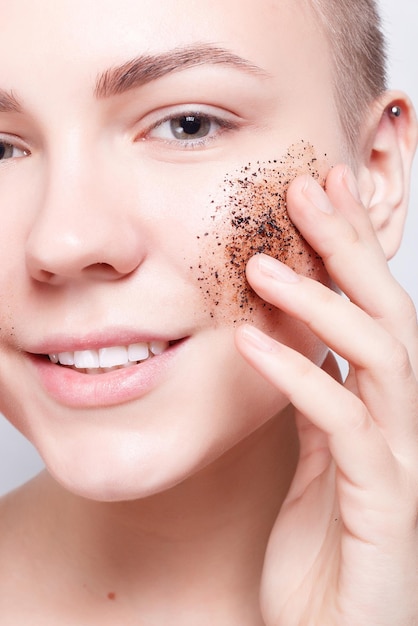 Health, people, Skin Care, youth and beauty concept - Smiling woman with short hair, bald cleans the skin coffee skrub, studio shot, close-up portrait. Clean Fresh Skin close up. Spa Woman Smiling