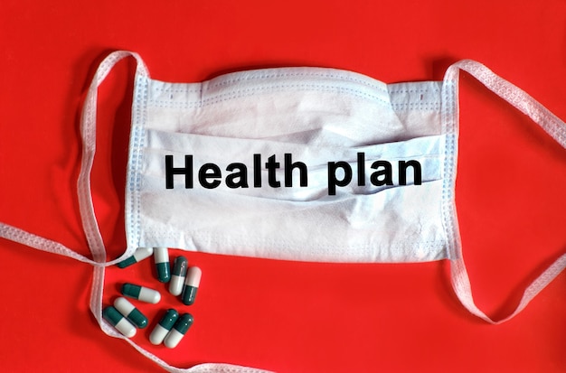 Health plan - text on a protective face mask, tablets on a red background