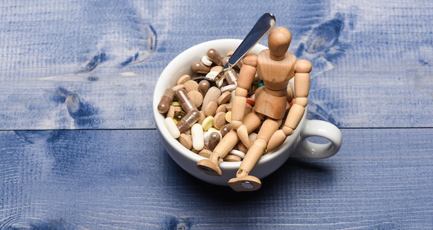 Health problem immunity care and medicine vitamins mixing\
medicines fast treatment take medicine concept medicines dose\
wooden human dummy near cup full pills and tablets vitamin\
cocktail