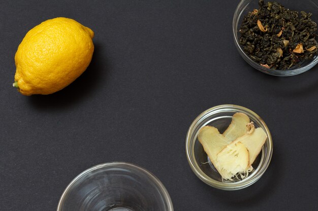 Health remedy foods for cold and flu relief with lemon, ginger and green tea on a black background. Top view. Foods That Boost the Immune System.