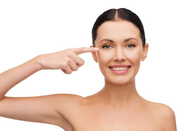 health, spa and beauty concept - clean face of beautiful young woman pointing to her eye