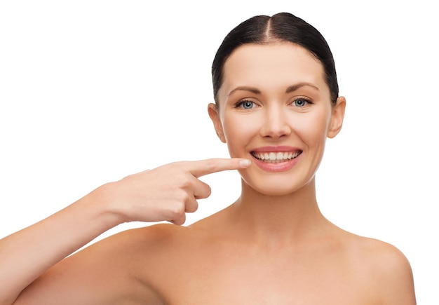 health, spa and beauty concept - clean face of beautiful young woman pointing to her mouth