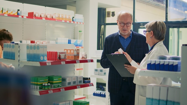 Health specialist giving cardioloy pills medicine to ill adult in pain, suffering from heartburn and cardiovascular problem. Elderly client looking for heart treatment and medicaments. Tripod shot.