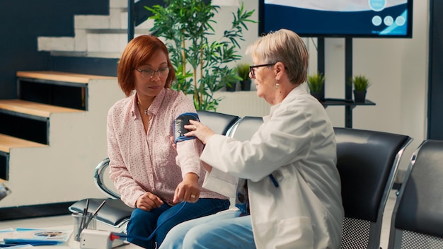 待合室で眼圧計を使って心臓検査を行うために、高血圧と血圧を測定する健康専門家。心臓病器具、病院の診療所でアジアの女性に相談する医師。