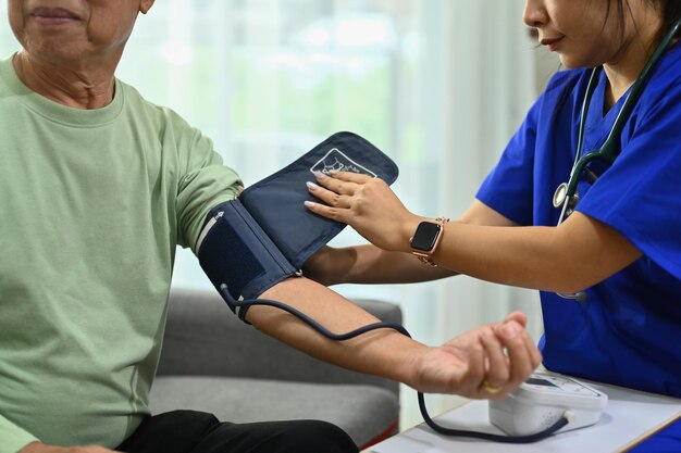 Health visitor measuring blood pressure senior man at home Elderly healthcare concept