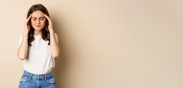 頭のこめかみに触れて気分が悪く、頭痛の片頭痛を感じている女の子の健康と女性のコンセプトポートレート