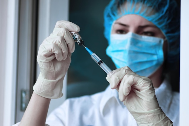 Медицинский работник набирает вакцину в шприц