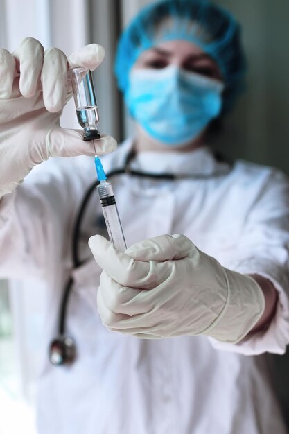 Медицинский работник набирает вакцину в шприц