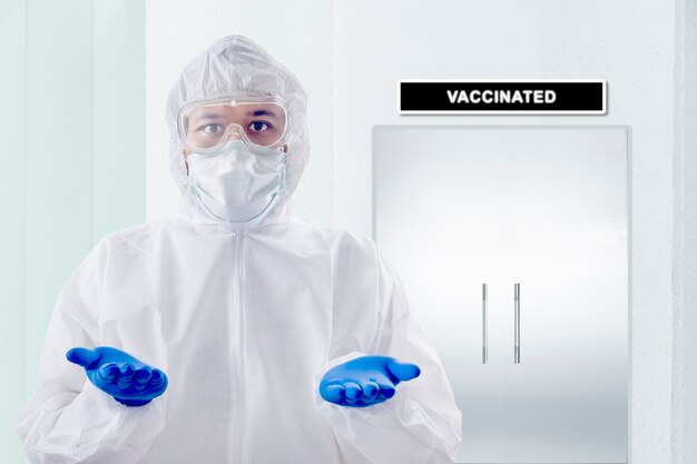 Health worker man with a protective suit and gloves standing with an open palm on the hospital