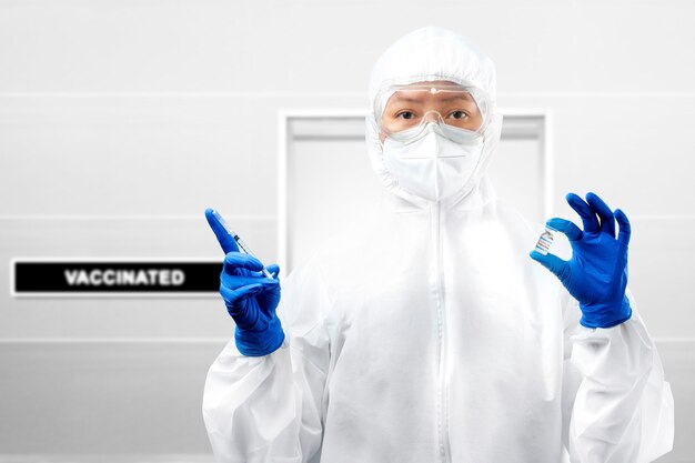 Health worker woman with a protective suit and gloves holding covid 19 vaccines on the hospital