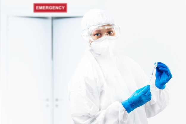 Health worker woman with a protective suit and gloves holding covid 19 vaccines on the hospital