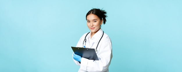 Foto concetto di assistenza sanitaria e clinica sorridente medico coreano donna medico in uniforme medica che tiene clipb