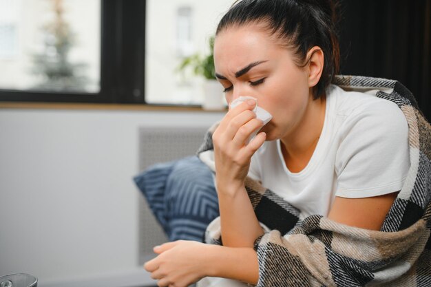 Фото Здравоохранение холодная аллергия и концепция людей больная женщина сморкается в бумажную ткань дома