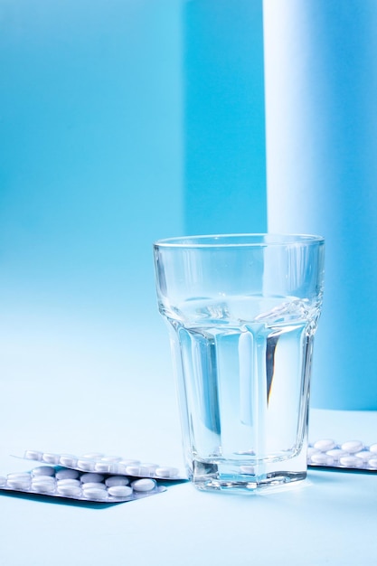 Healthcare concept on blue glass of water with pills