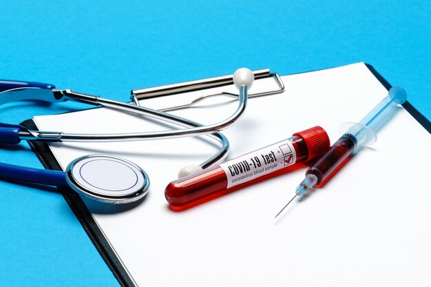 Healthcare concept - Covid-19 negative blood test tube, stethoscope, syringe and clipboard with