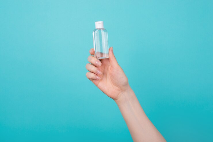Photo healthcare concept. cropped photo of woman holding a small bottle of hand sanitizer isolated on blue teal turquoise background