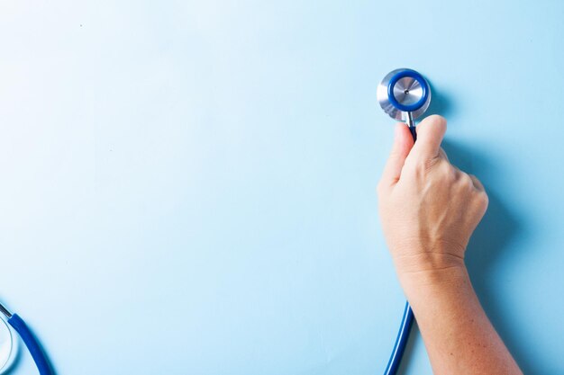 Foto concetto di assistenza sanitaria con la mano che tiene lo stetoscopio su sfondo blu