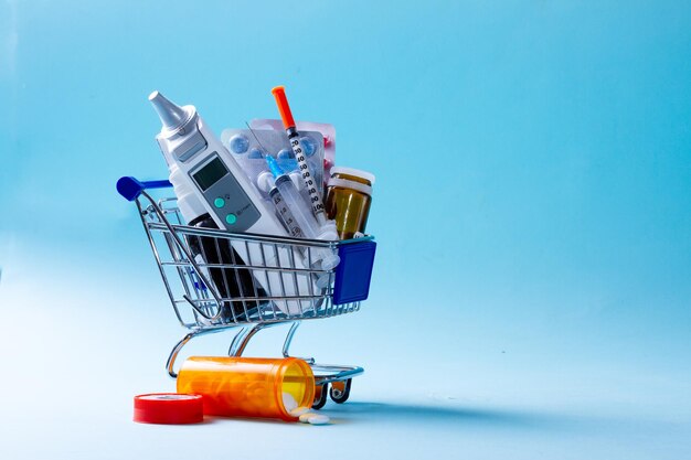 Healthcare concept medical tools and medicaions in shopping cart on blue background