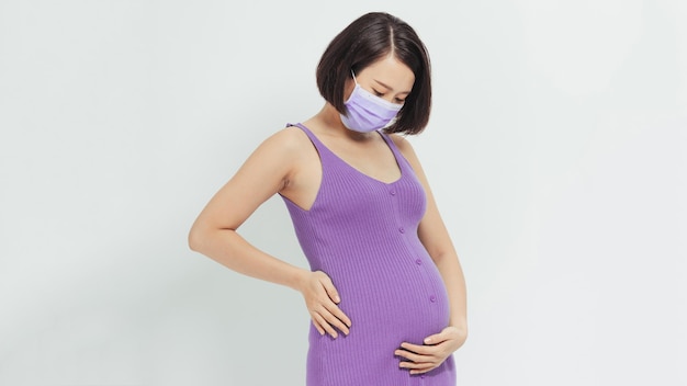 Healthcare conceptAsian pregnant woman in protective mask against flu and viruses white background