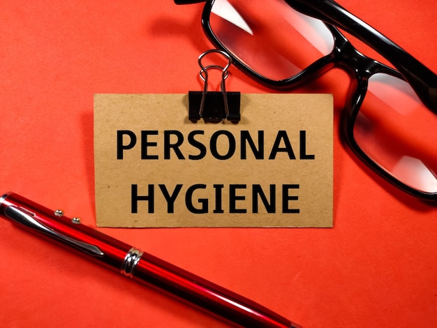 Healthcare concepttext personal hygiene writing on brown card
with glasses and pen on red background