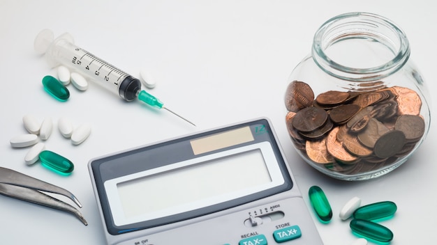Концепция стоимости здравоохранения, калькулятор, пинцет, таблетки и шприц на белом фоне