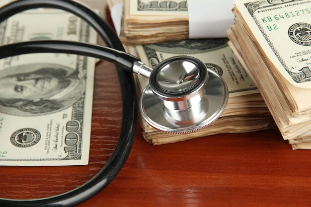 Концепция стоимости здравоохранения стетоскоп и доллары на деревянном фоне