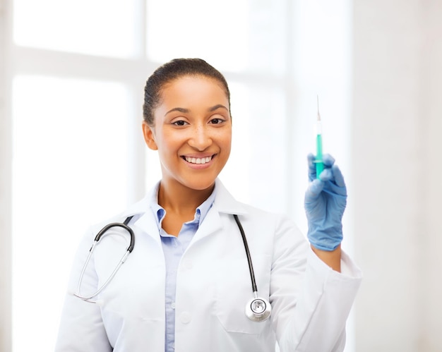 healthcare and medical concept - african doctor holding syringe with injection