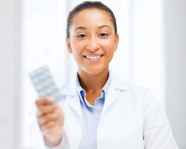 healthcare and medical concept - african doctor with blister packs of pills