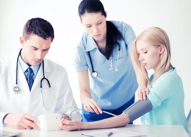 ヘルスケアと医療の概念-病院で血圧を測定する患者と医師と看護師