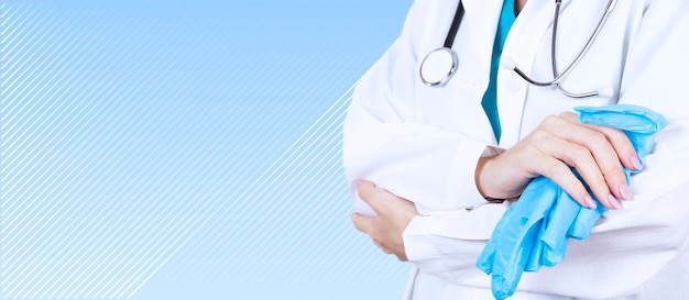 Healthcare and medical concept. A doctor with a stethoscope in his hand, in a white coat and blue gloves with crossed arms. Side view. Copy space. High quality photo