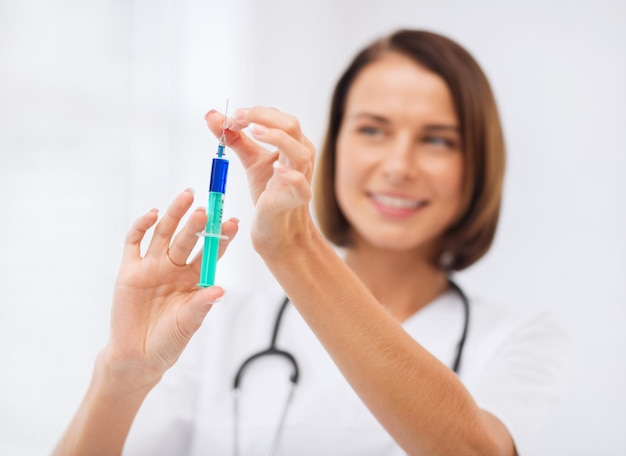 healthcare and medical concept - female doctor holding syringe with injection