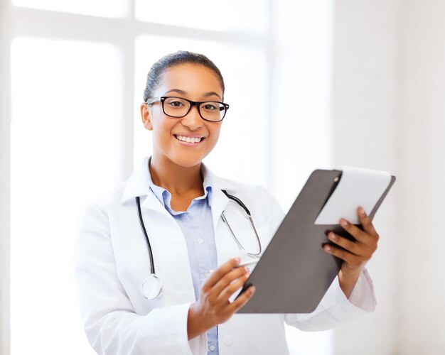 healthcare and medical concept - smiling african female doctor with prescription in hospital