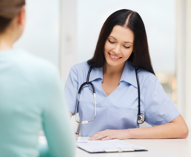 healthcare and medical concept - smiling female doctor or nurse with patient writing prescription