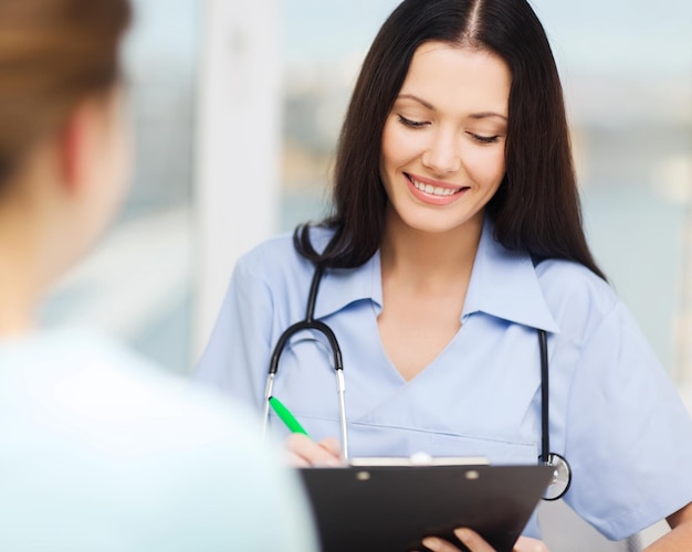 healthcare and medical concept - smiling female doctor or nurse with patient writing prescription