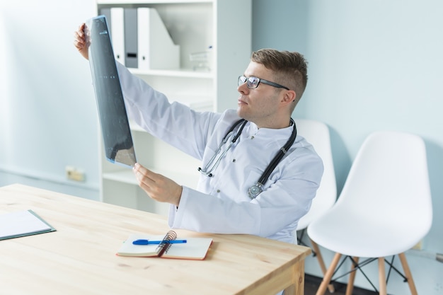 Healthcare, medical and people concept - doctor examines an x-ray sitting behind a desk