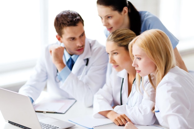 healthcare, medical and technology concept - group of doctors looking at laptop