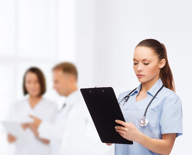 의료 및 의학 개념 - 청진기와 클립보드가 있는 심각한 여성 의사 또는 간호사