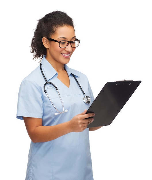 концепция здравоохранения и медицины - улыбающаяся афроамериканка-врач или медсестра в очках со стетоскопом и буфером обмена