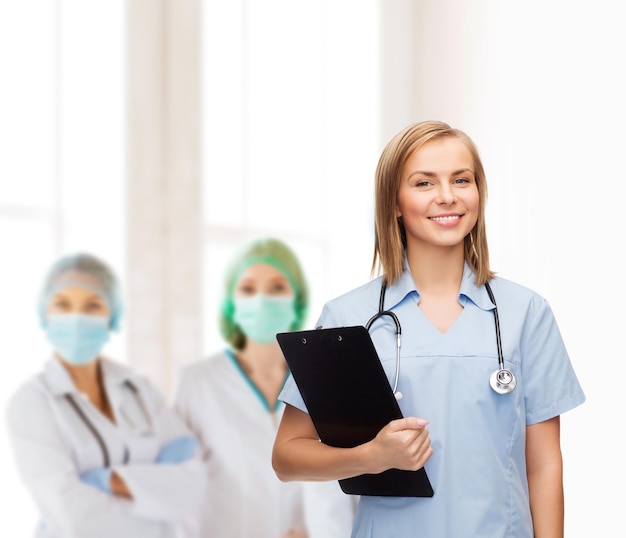 의료 및 의학 개념 - 클립보드와 청진기를 들고 웃는 여성 의사 또는 간호사