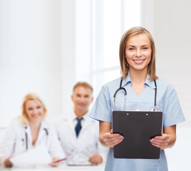 концепция здравоохранения и медицины - улыбающаяся женщина-врач или медсестра с буфером обмена и стетоскопом