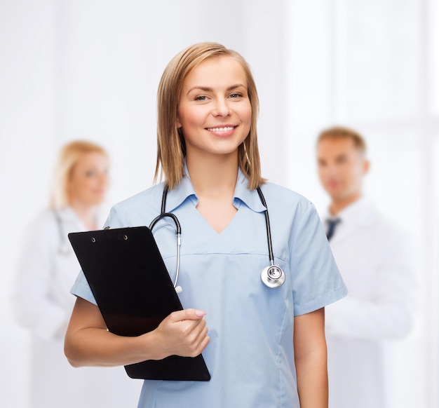 healthcare and medicine concept - smiling female doctor or nurse with clipboard and stethoscope