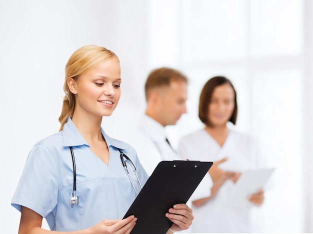 healthcare and medicine concept - smiling female doctor or nurse with stethoscope and clipboard