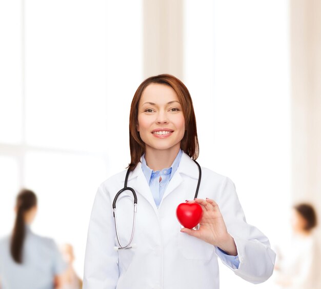 healthcare and medicine concept - smiling female doctor with heart and stethoscope