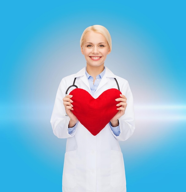 Healthcare and medicine concept - smiling female doctor with heart and stethoscope