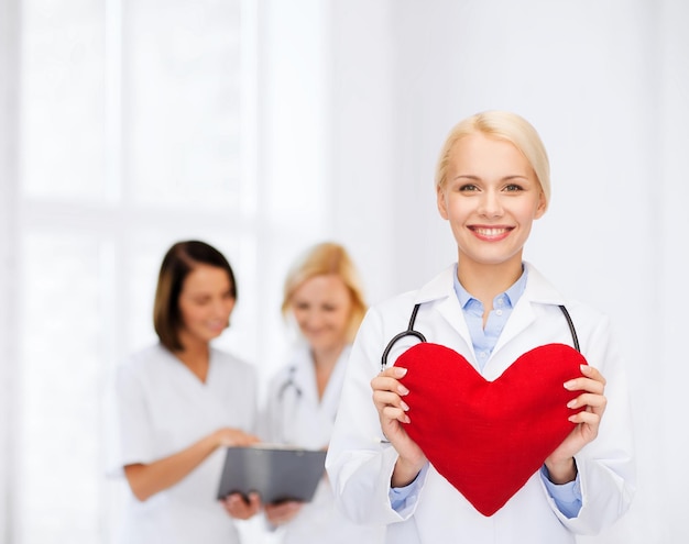 концепция здравоохранения и медицины - улыбающаяся женщина-врач с сердцем и стетоскопом