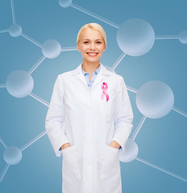 healthcare and medicine concept - smiling female doctor with pink cancer awareness ribbon over molecular background