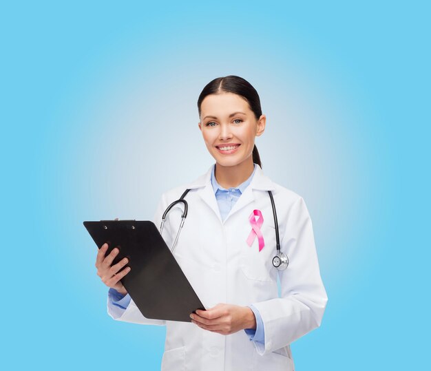 healthcare and medicine concept - smiling female doctor with stethoscope, clipboard and pink cancer awareness ribbon over blue background