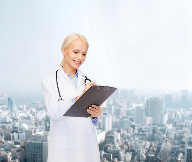 healthcare and medicine concept - smiling female doctor with stethoscope and clipboard